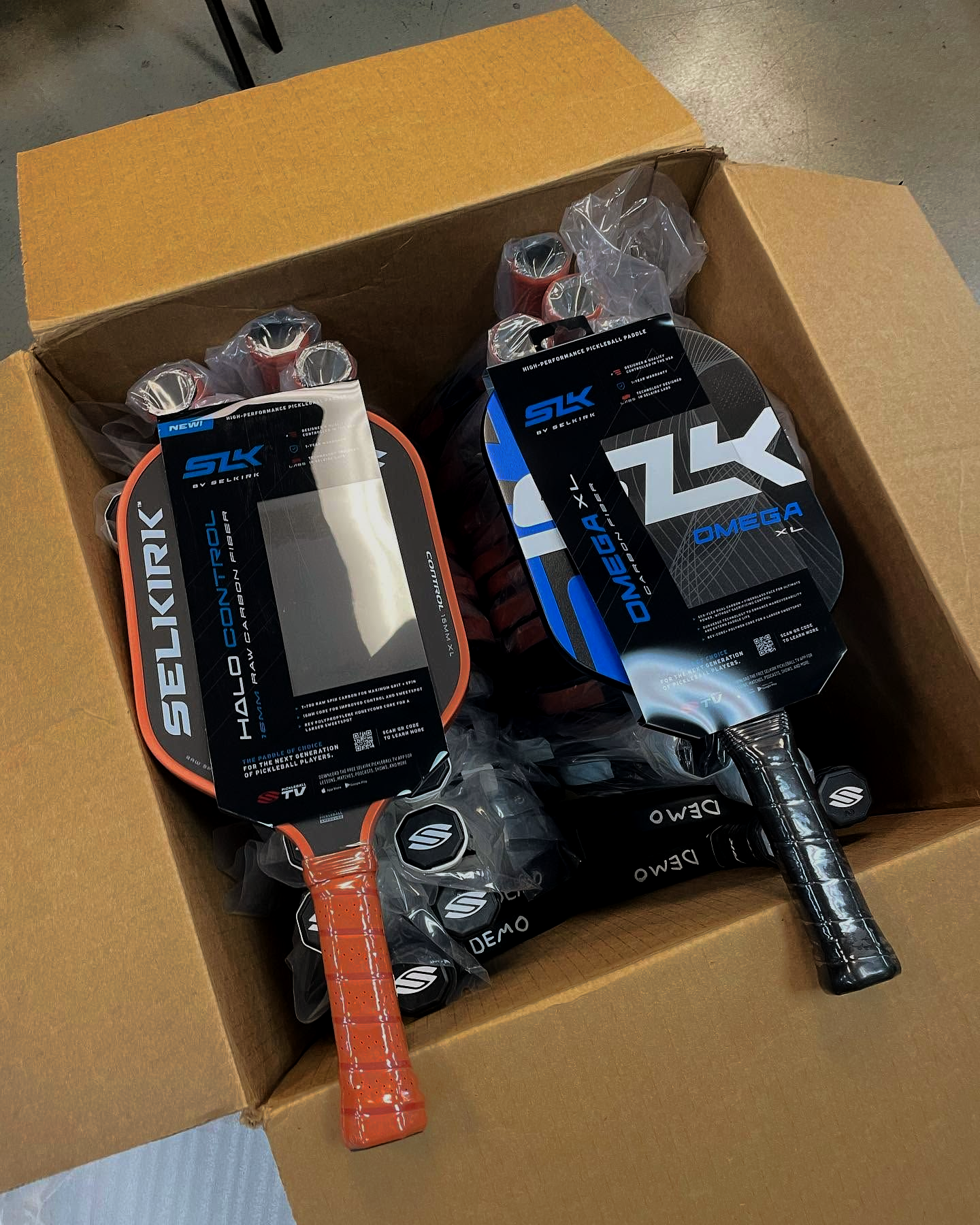 Open box with two Selkirk pickleball paddles in black, orange, and silver packaging.