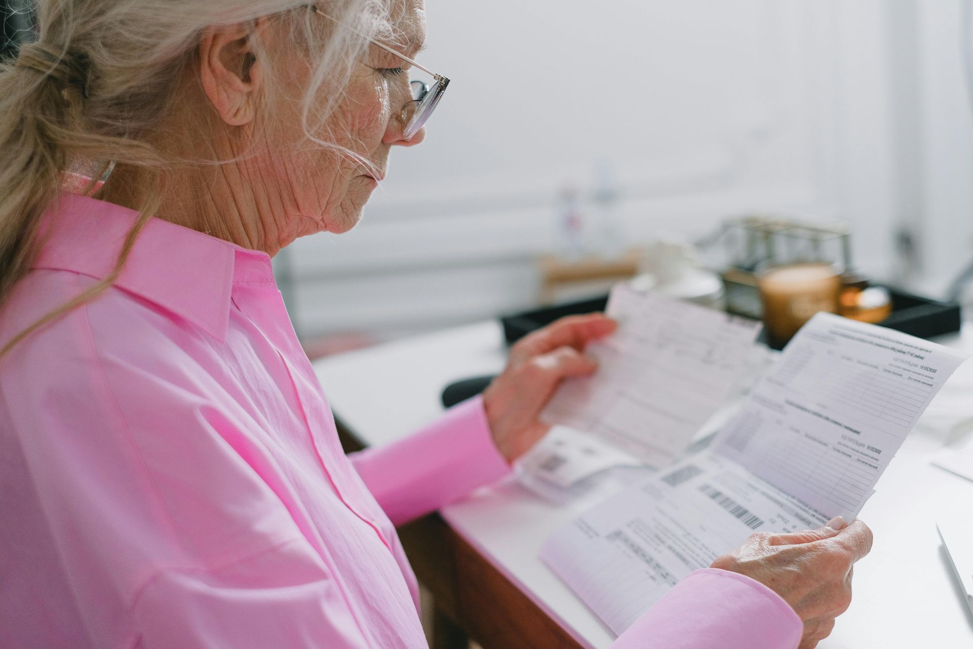 Person in a pink shirt reading documents at a desk