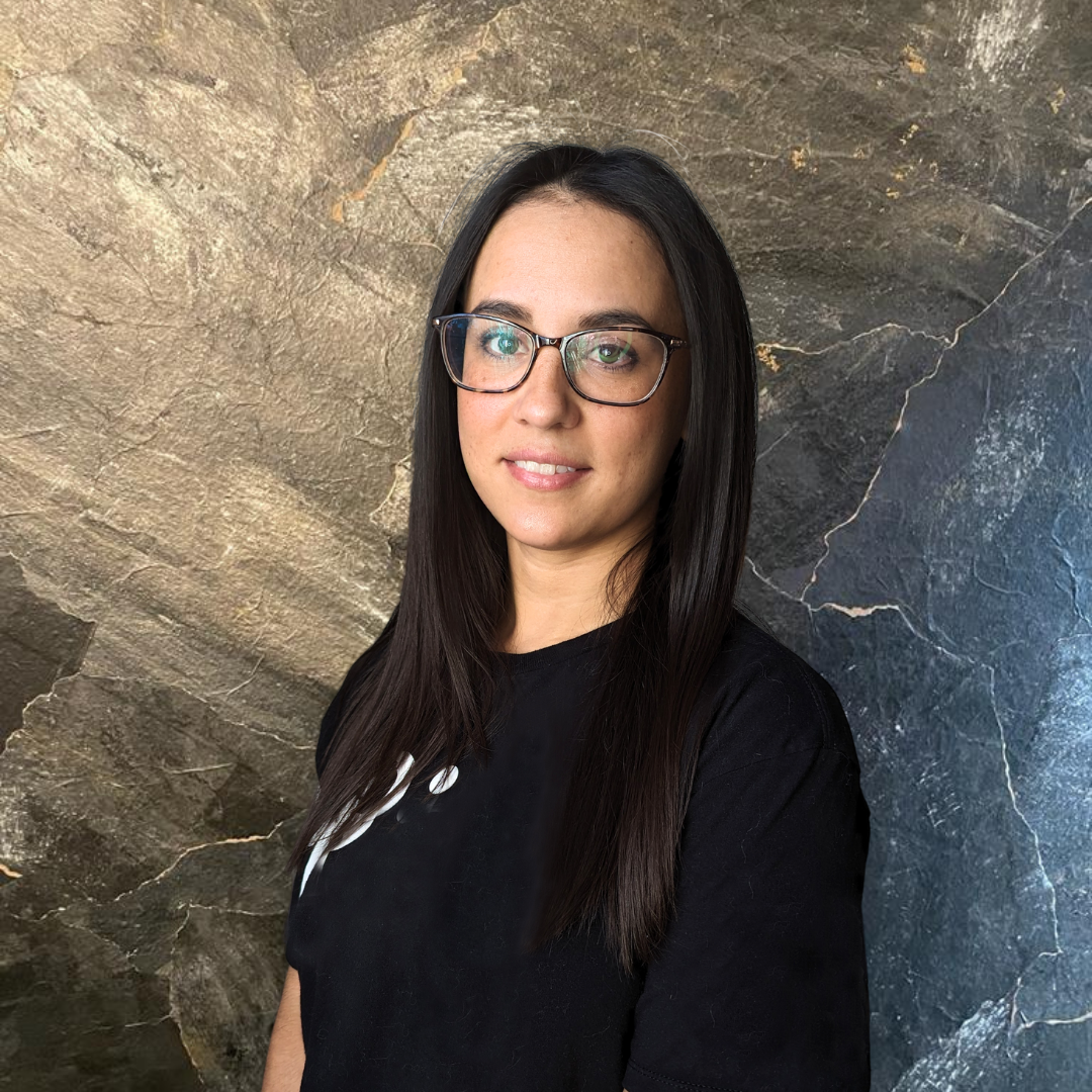 a woman wearing glasses and a black shirt smiles to the camera