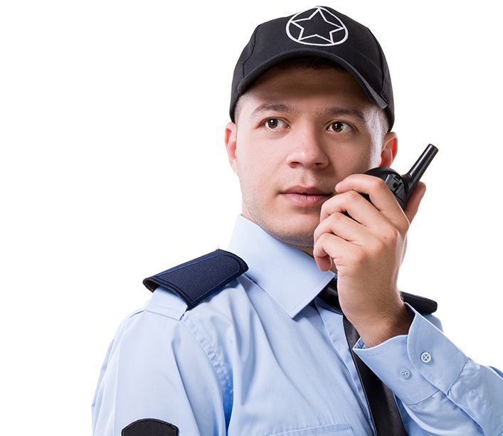 Security guard holding a walkie-talkie, wearing a uniform and a black cap with a star emblem, looking alert.