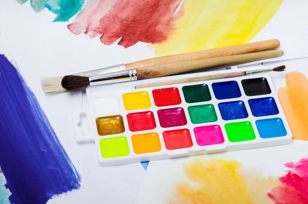 Colori ad acquerello con pennelli e una tavolozza di colori su carta