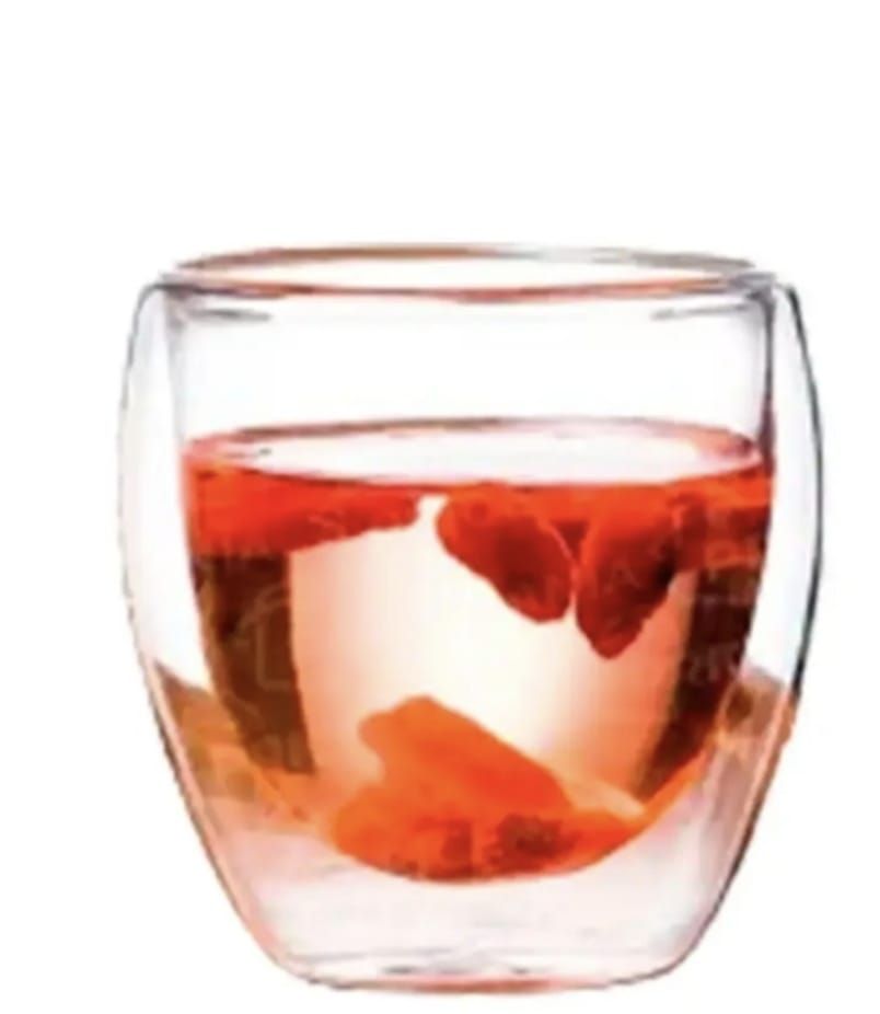 Vaso de vidrio de doble pared con líquido rosa y bayas anaranjadas.