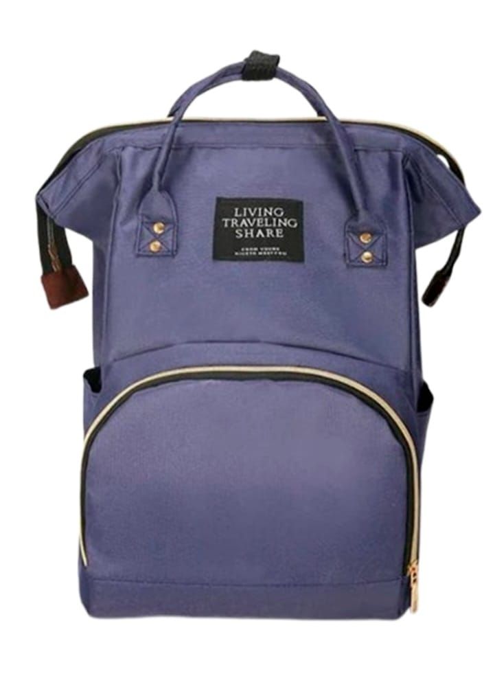 Bolso cambiador morado con cremalleras doradas y etiqueta “Living Traveling Share”.