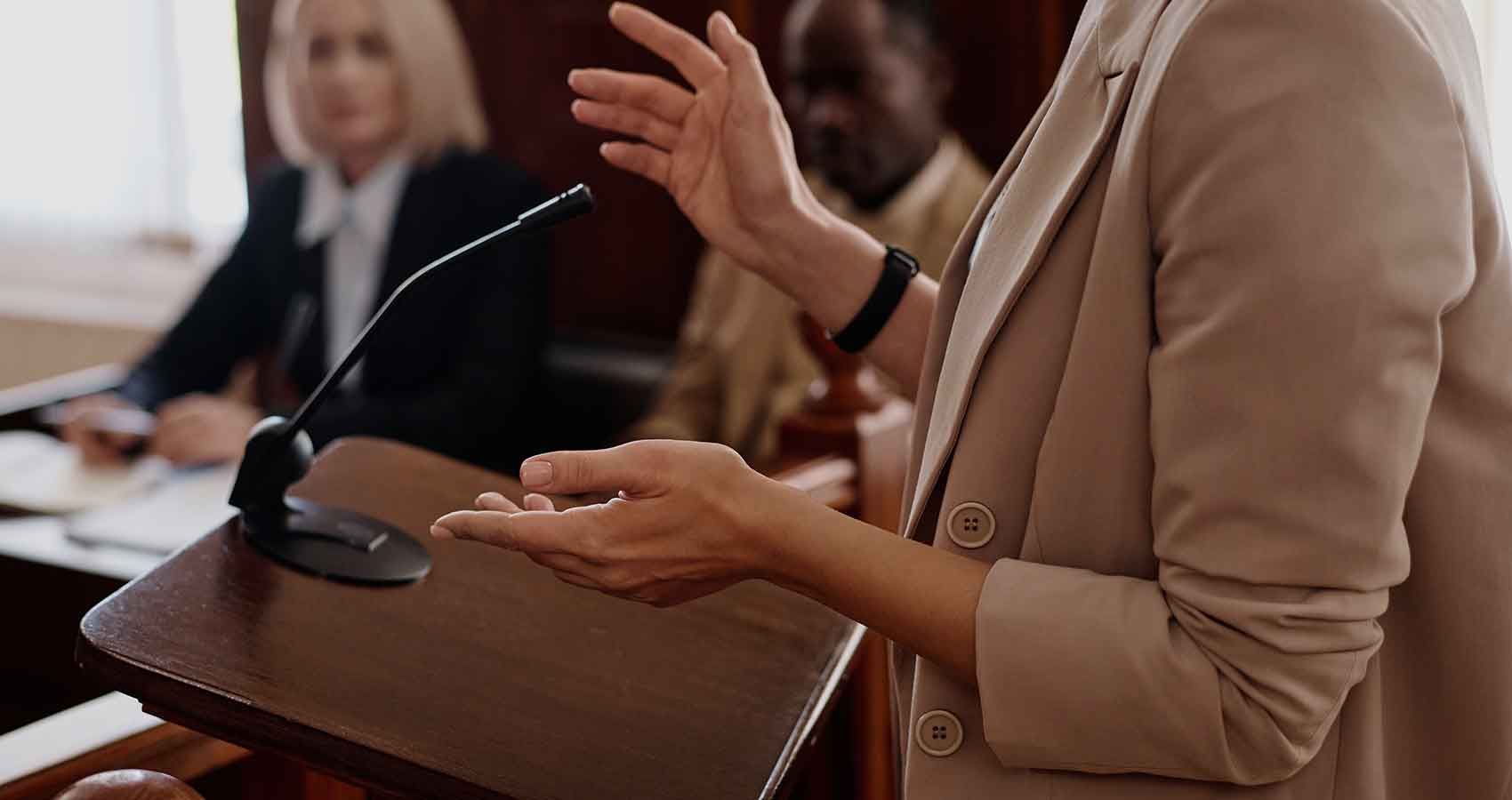 A woman is giving a speech in front of a microphone in a courtroom.