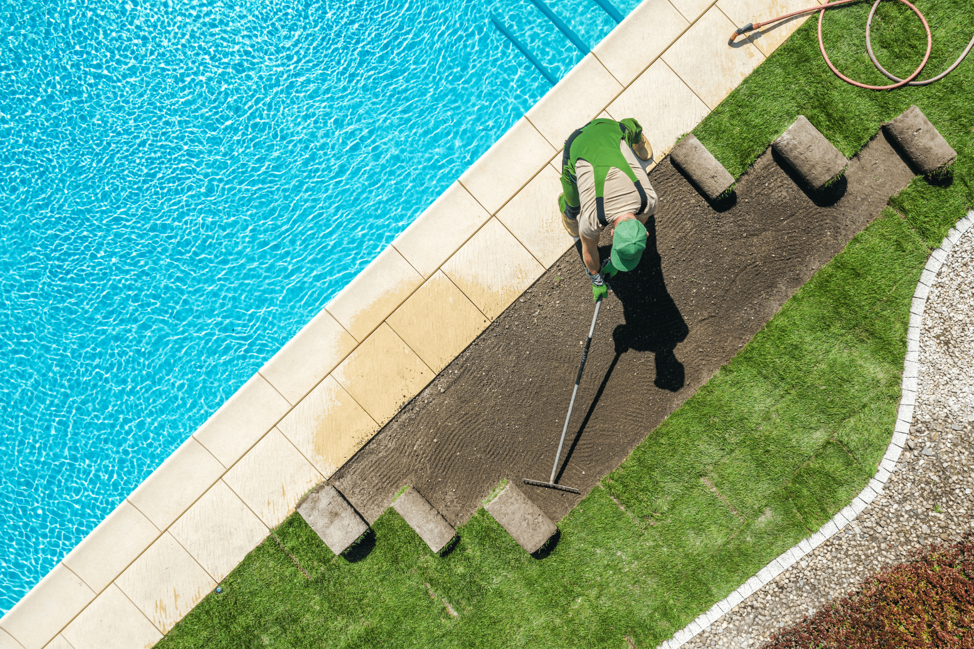 Landscaper raking the soil before installating new grass turfs around the swimming pool
