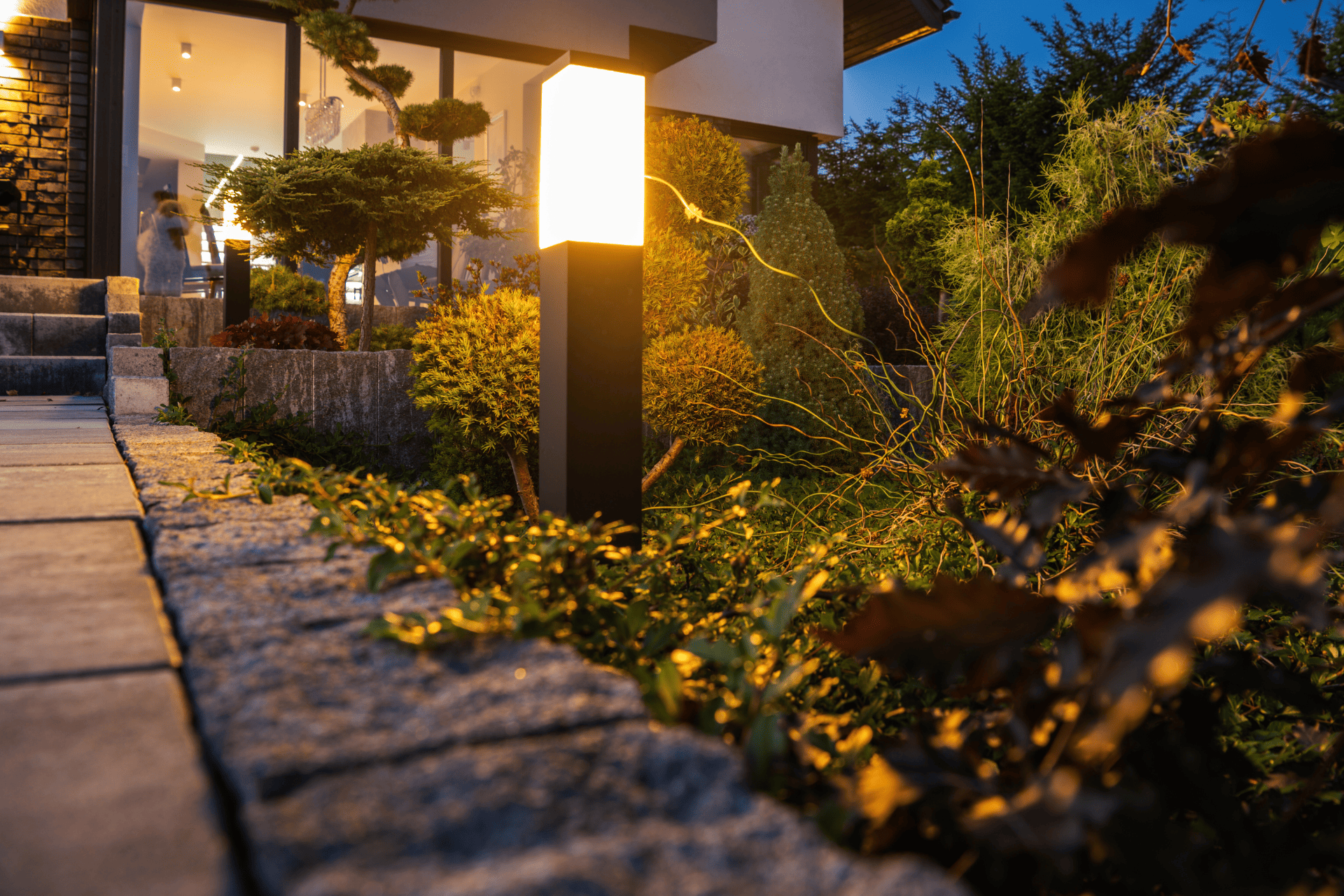 Bright outdoor lighting lighting up walkway of landscaped backyard at night