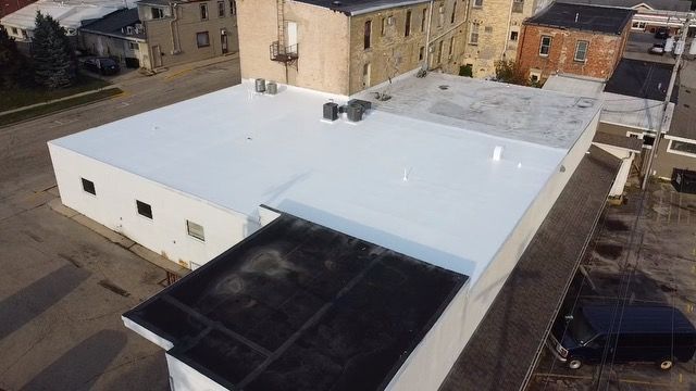 An aerial view of a building with a white roof and a black roof.