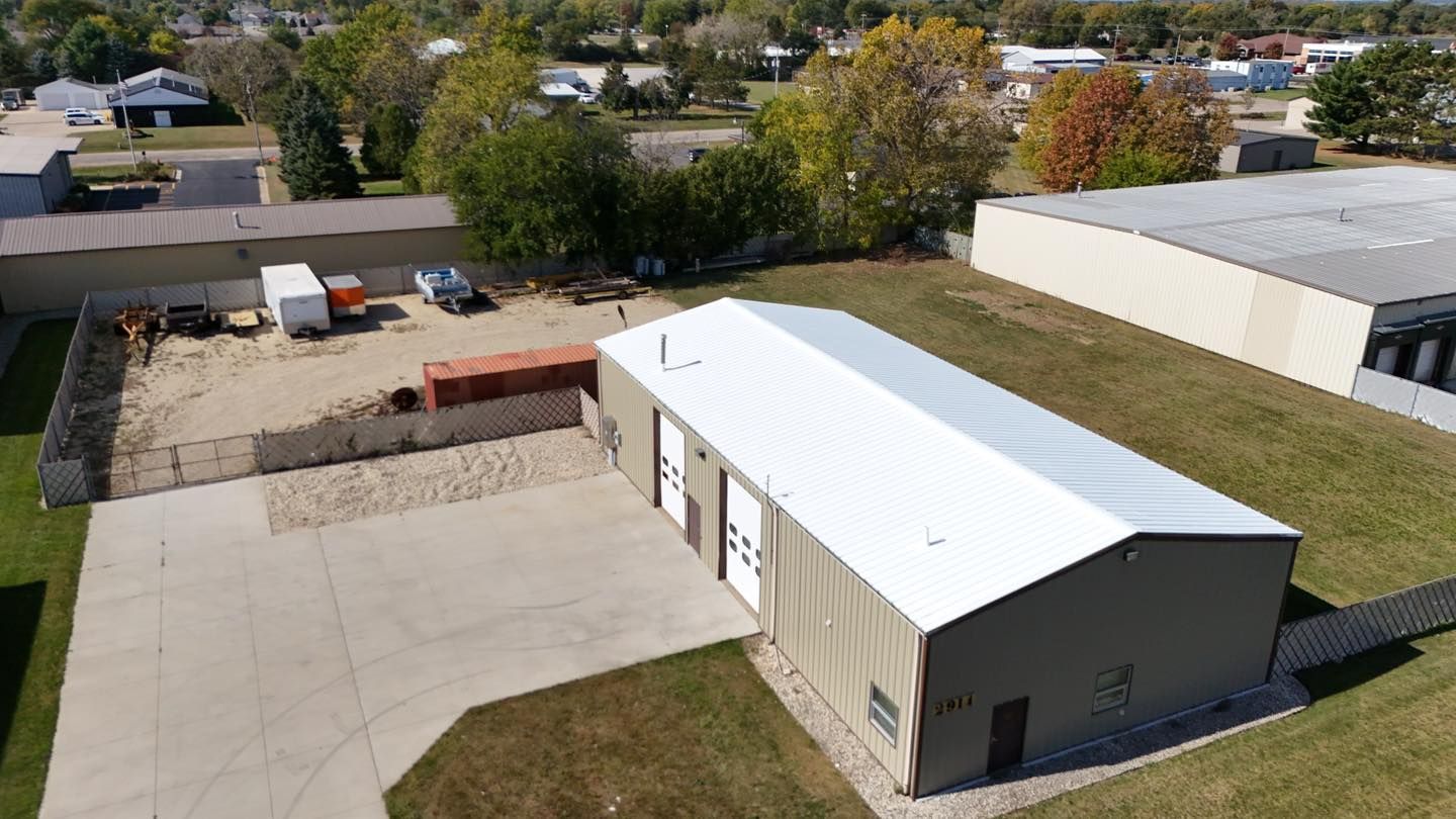 An aerial view of a large building with a white roof in a residential area.