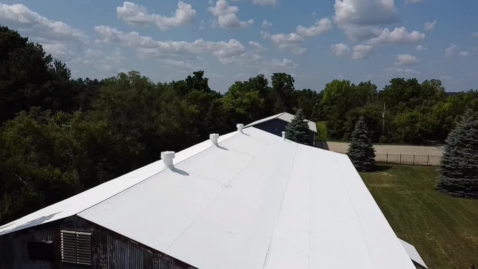 An aerial view of a white roof with trees in the background.