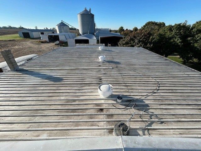 The roof of a building with a silo in the background.