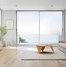 Soggiorno moderno con grande porta scorrevole in vetro che si affaccia su una recinzione bianca e sull'acqua.