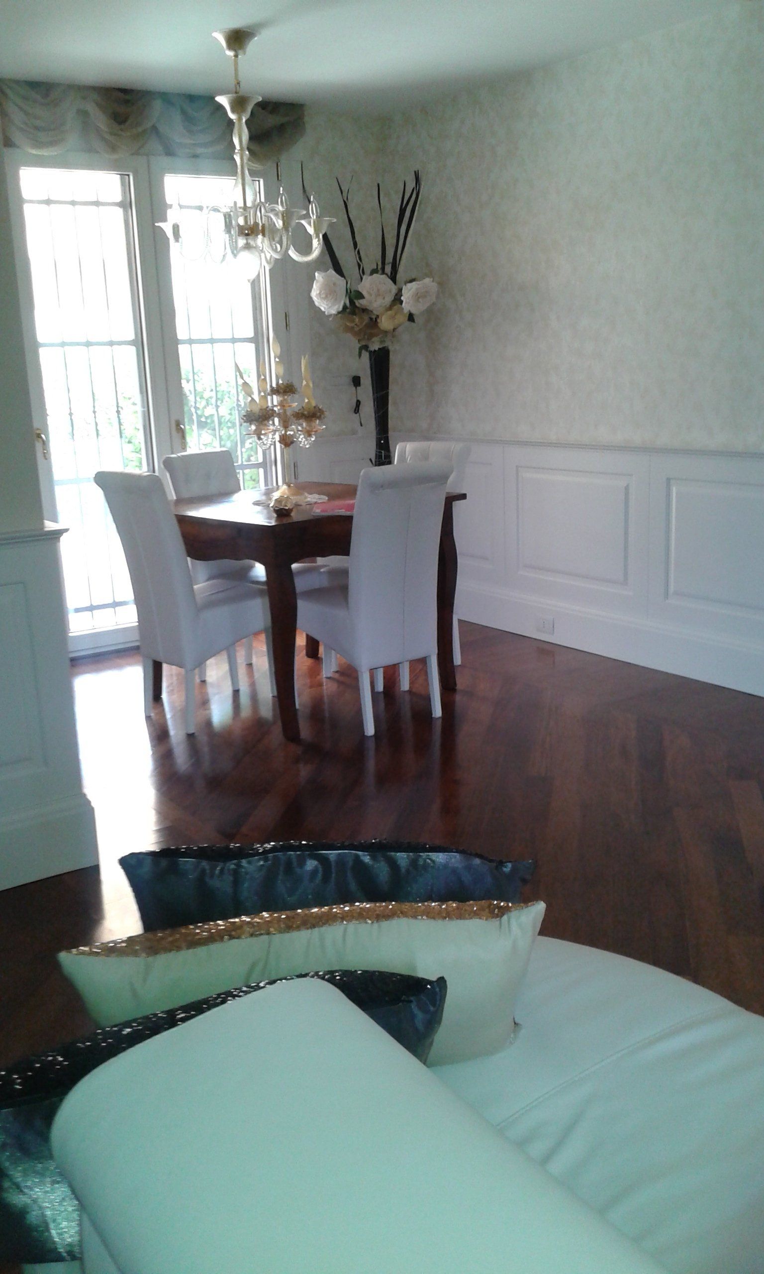 Sala da pranzo con tavolo, sedie, pavimenti in legno e porta-finestra.