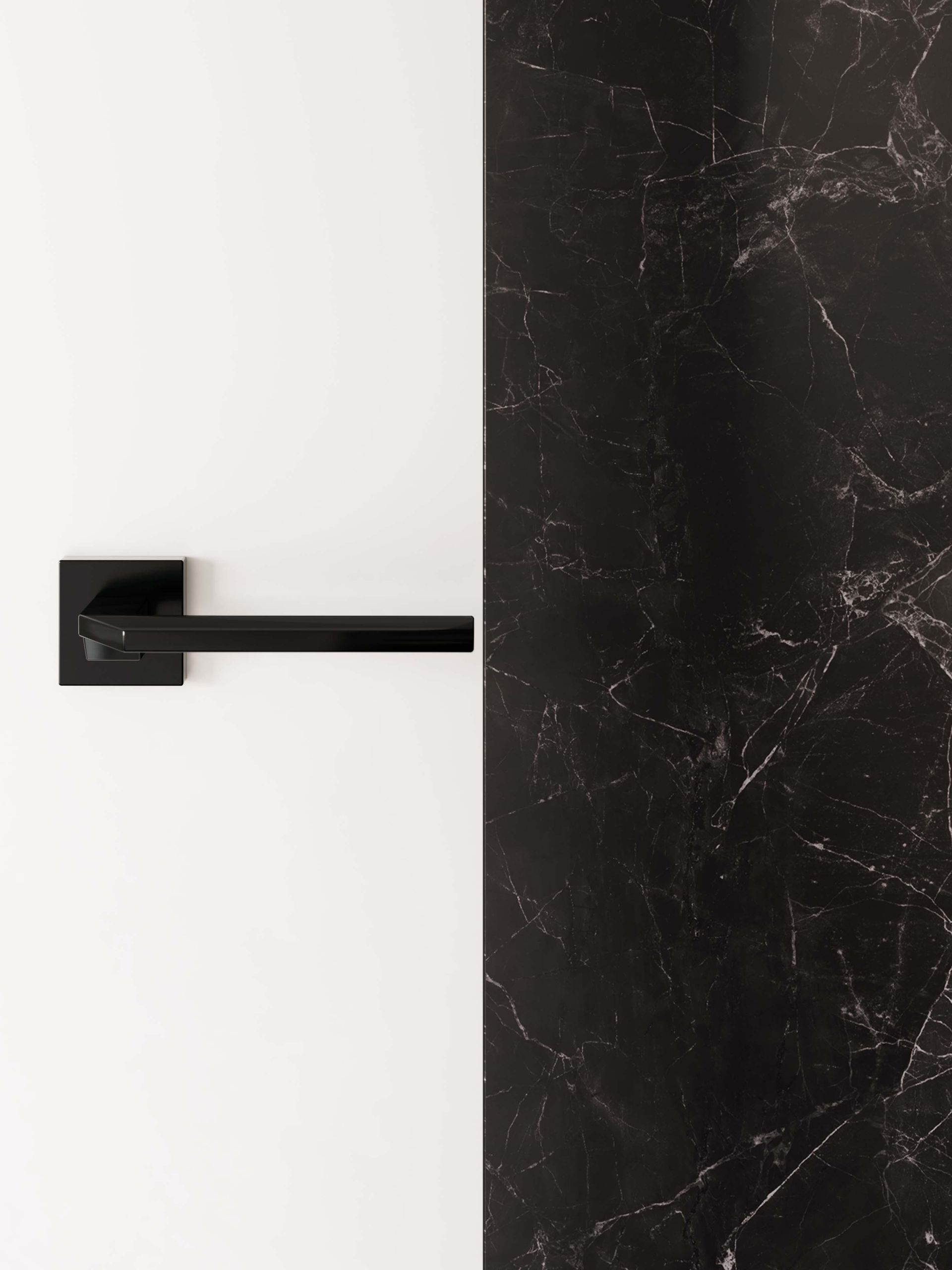 Maniglia nera su porta bianca accanto a parete in marmo nero.