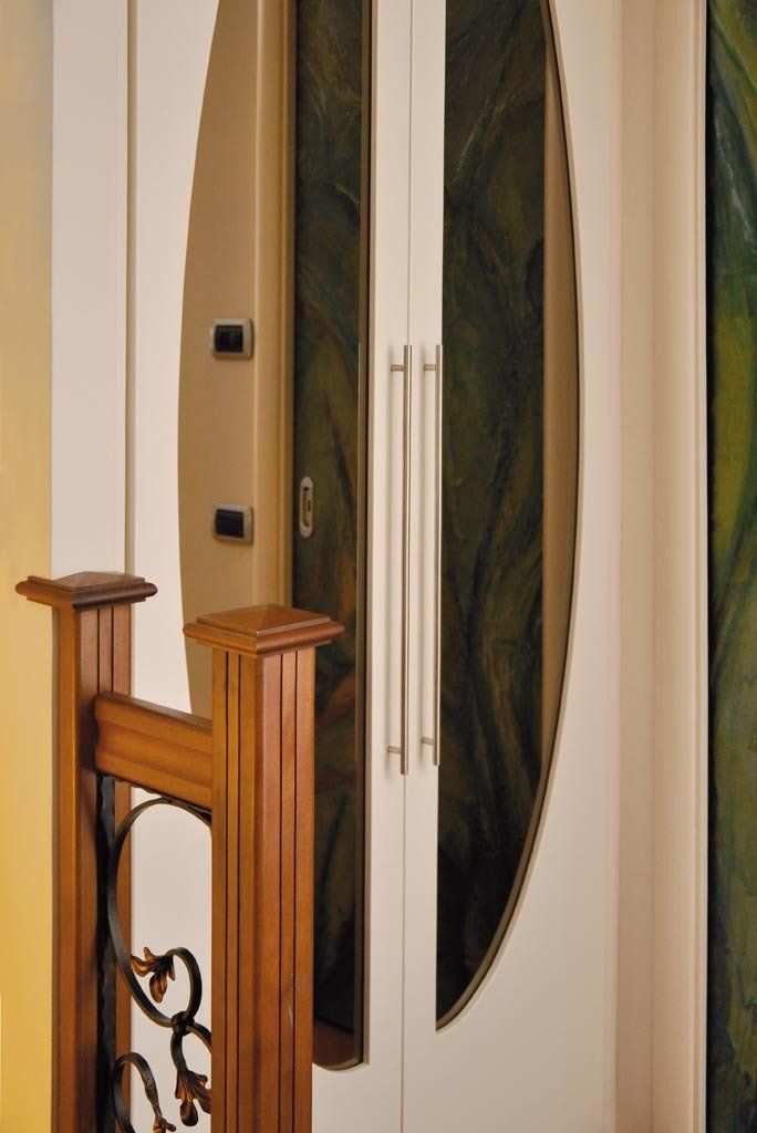 Ringhiera in legno e porta con pannello ovale in vetro e maniglie argentate.