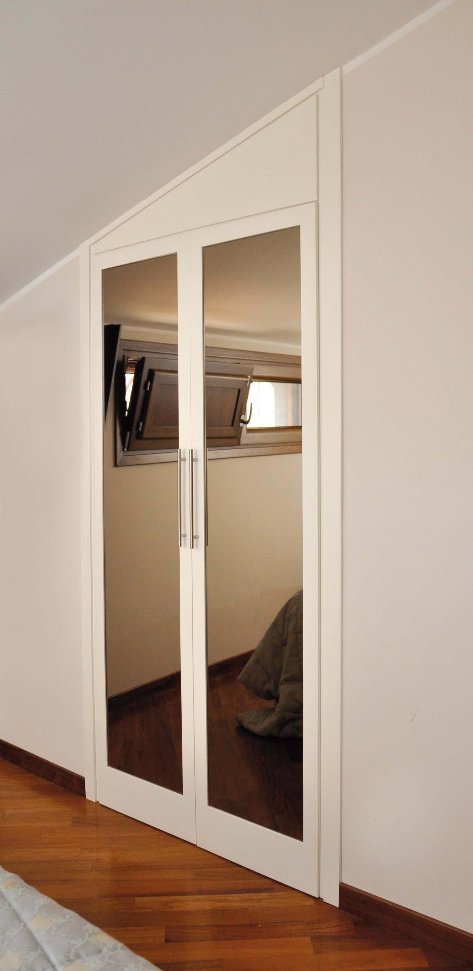 Ante dell'armadio a specchio in una stanza con pavimenti in legno e pareti bianche.