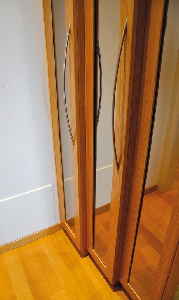 Ante in legno per armadi con superfici riflettenti, montate su un pavimento in legno.