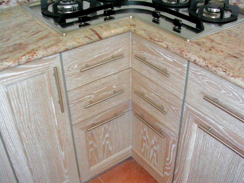 Mobili da cucina in legno chiaro con ferramenta dorata e piano di lavoro in granito maculato.