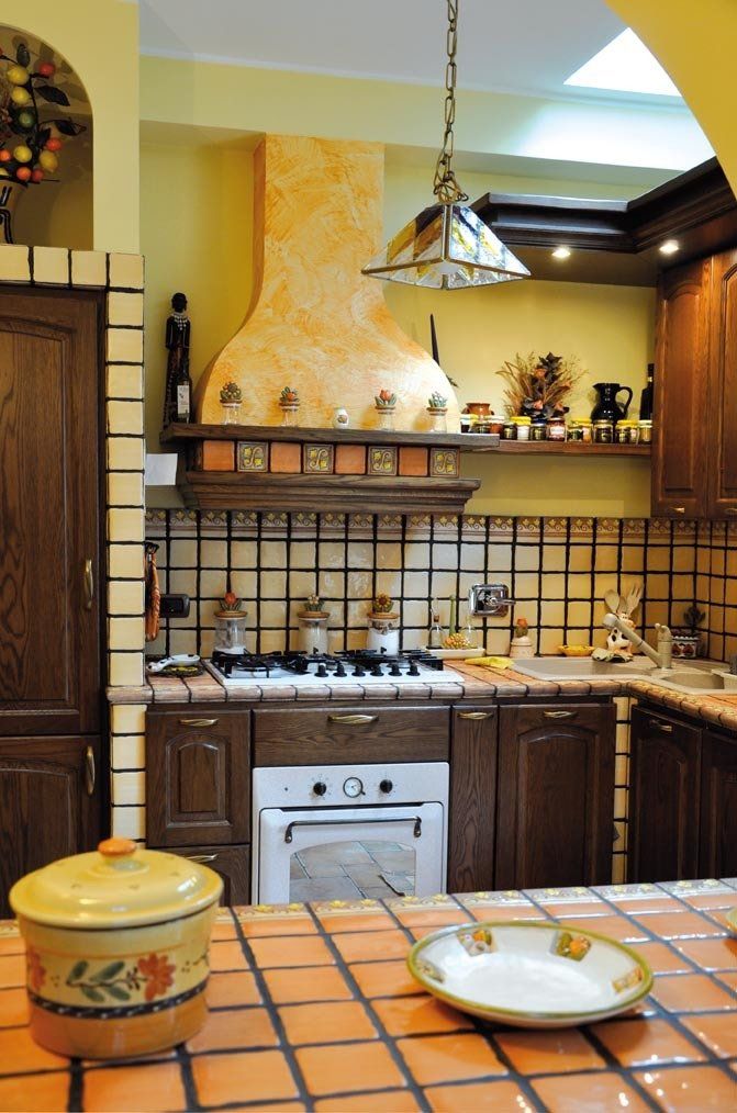 Cucina con mobili in legno scuro, stufa, paraschizzi e ripiani piastrellati.