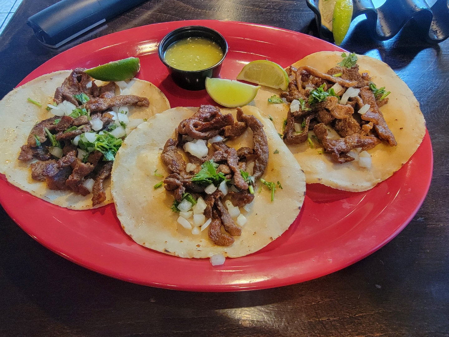 Quesabirria tacos with consommé dip on a red plate.