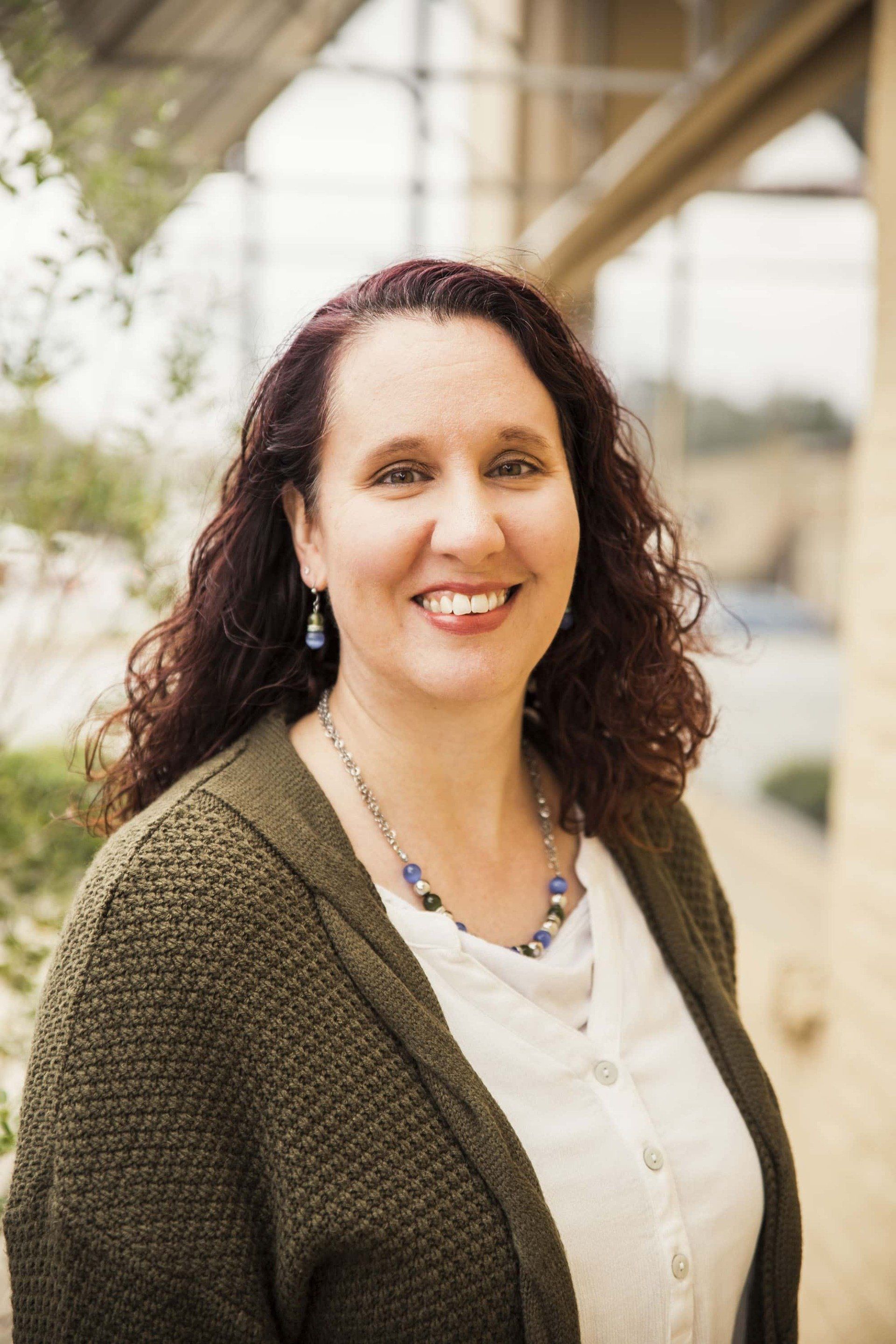 Rosemary Burns wearing a green sweater and a white shirt is smiling for the camera.