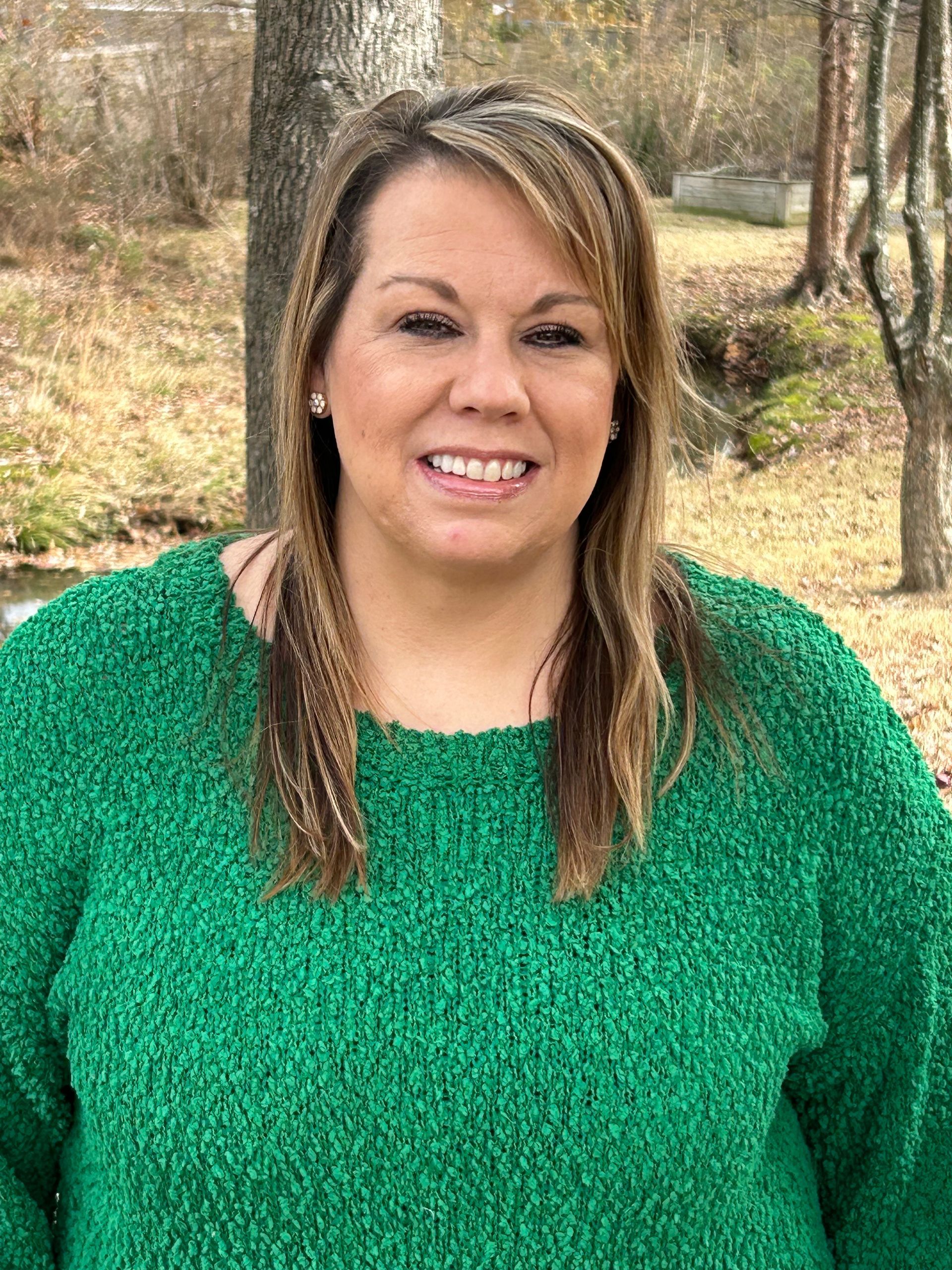 Ashly is wearing a green sweater and smiling for the camera.