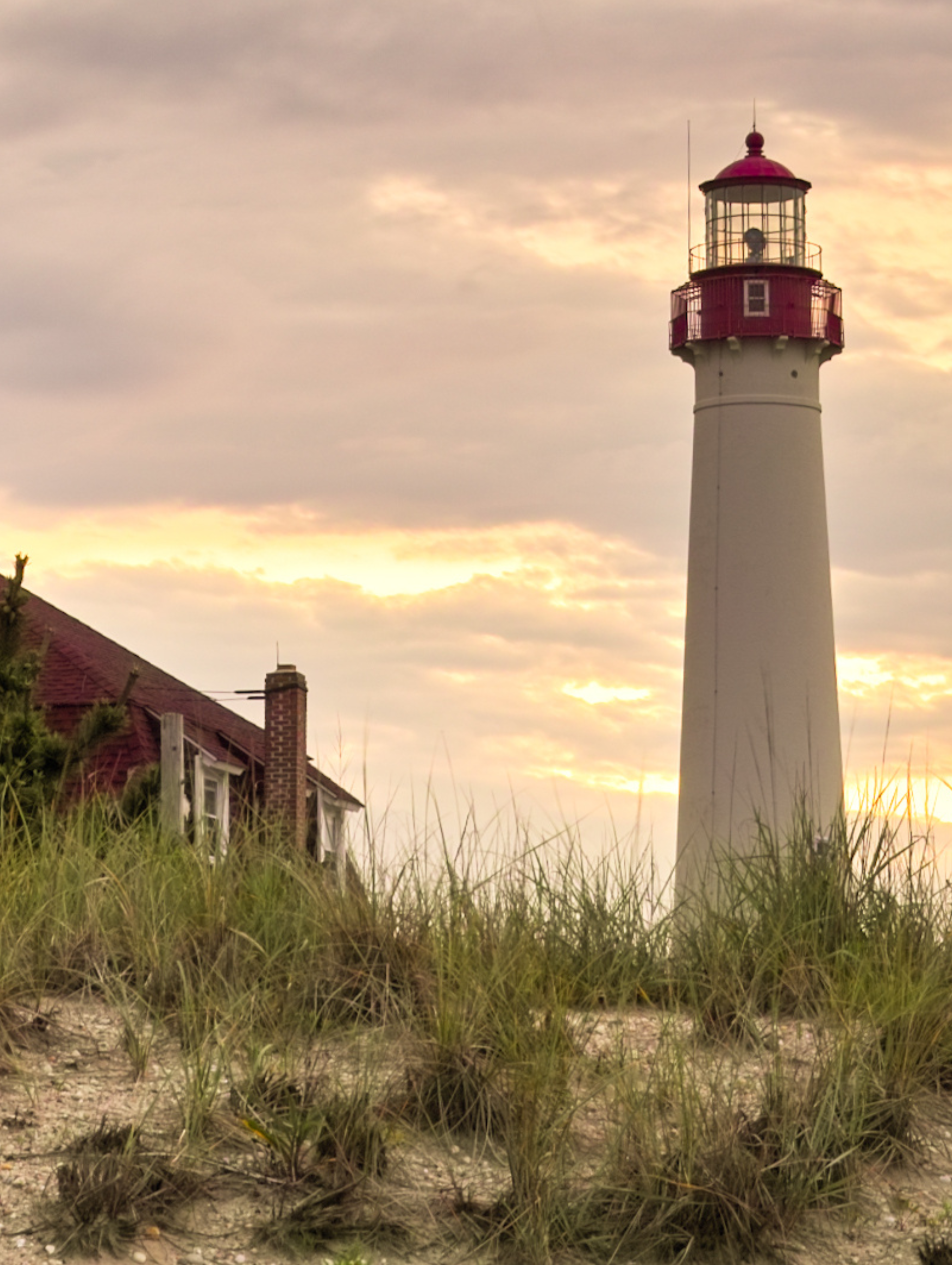 A lighthouse is sitting on top of a grassy hill.