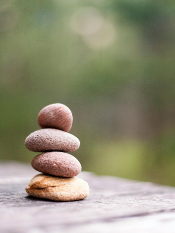 Een stapel van vier ronde stenen, in evenwicht op elkaar gestapeld, met een wazige groene achtergrond van InnerGuide Tools
