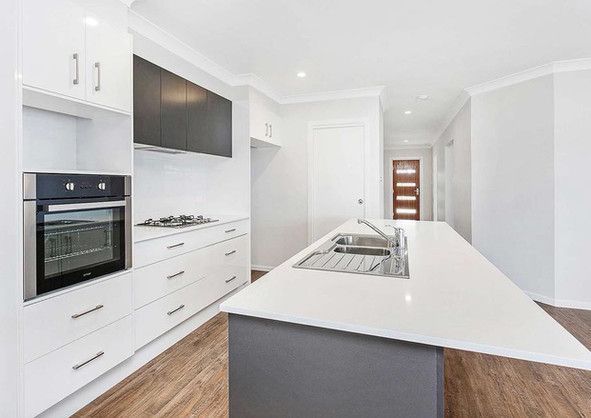 A kitchen with white cabinets, a sink, and a stove.