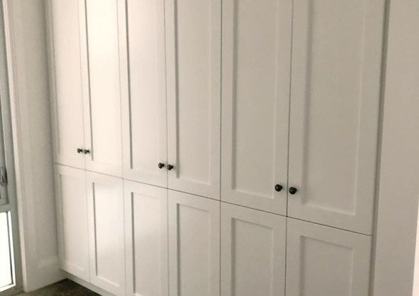 A room with a lot of white cabinets and a window.