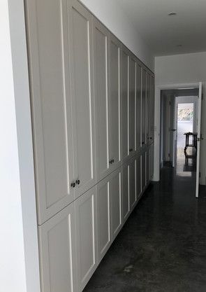 A hallway with a lot of white cabinets and a door.