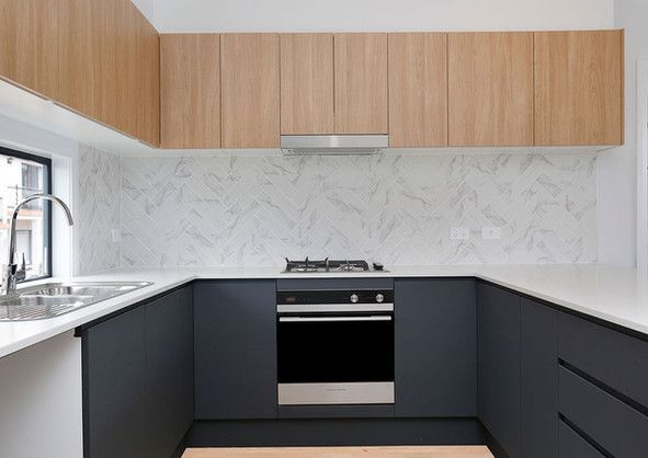 A kitchen with black cabinets , a stove, a sink, and a window.