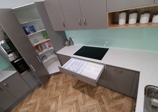A kitchen with a stove top oven and a drawer open.