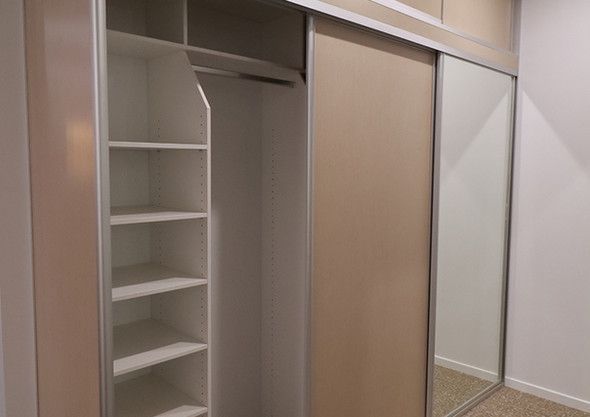 A walk in closet with sliding doors and a mirror.