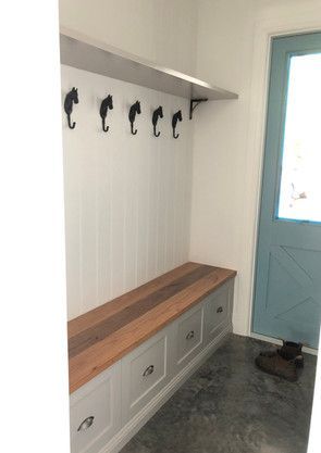 A hallway with a bench and hooks on the wall.