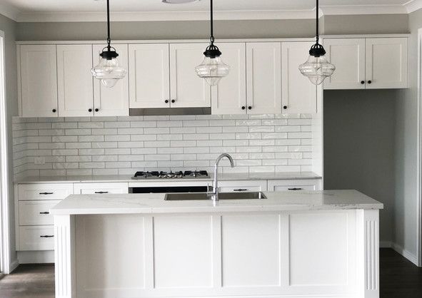 A kitchen with white cabinets, a sink, and a stove.