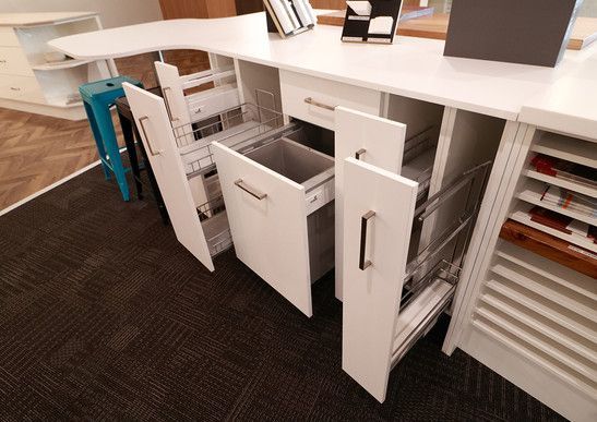 A kitchen with a trash can in the middle of the cabinets.
