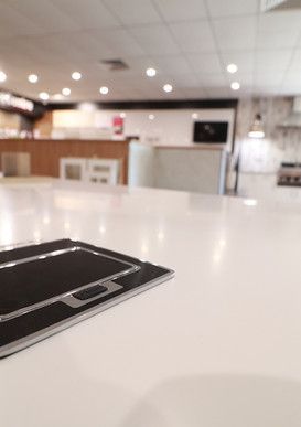A white counter top with a black tray on it in a kitchen.