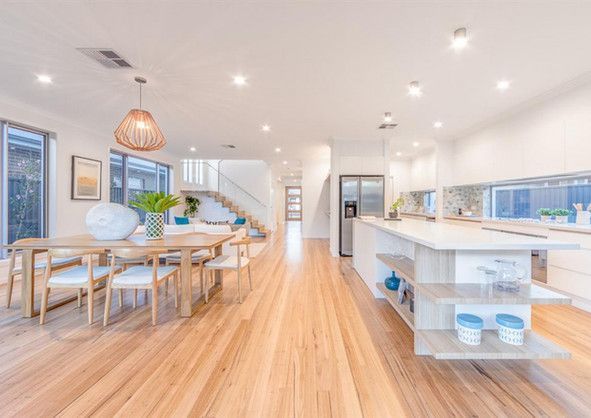 A kitchen and dining room in a house with wooden floors and white cabinets.