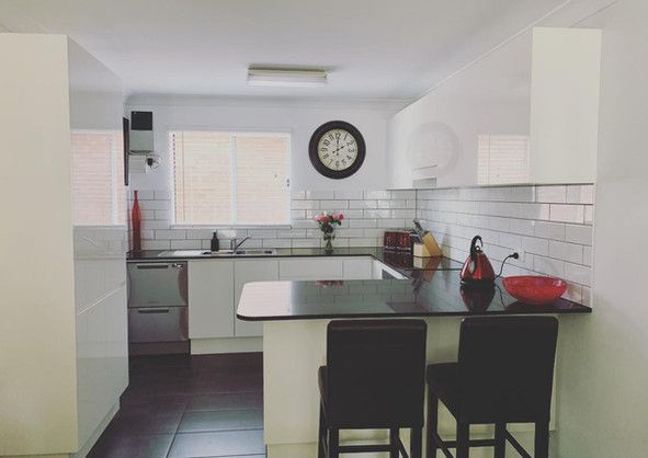 A kitchen with white cabinets and a clock on the wall.