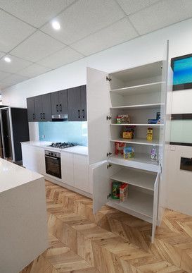 A kitchen with white cabinets and a pantry with the door open.