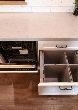 A kitchen with a dishwasher and a trash can in the drawer.