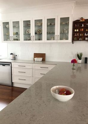 A kitchen with white cabinets and a bowl of fruit on the counter.