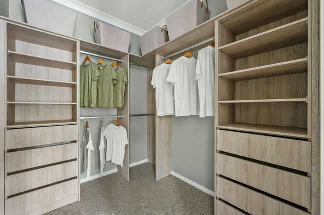 A walk in closet with clothes hanging on racks and shelves.