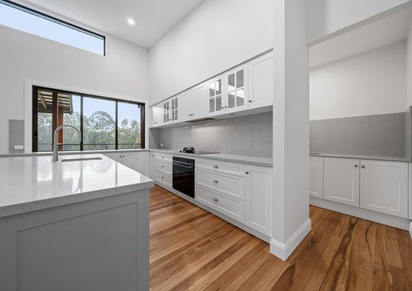 A kitchen with white cabinets and wooden floors.