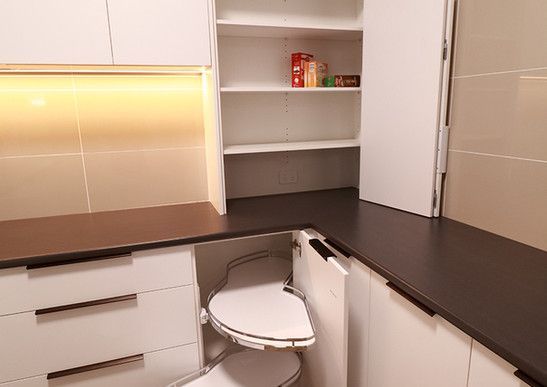 A kitchen with white cabinets and black counter tops and a trash can in the corner.