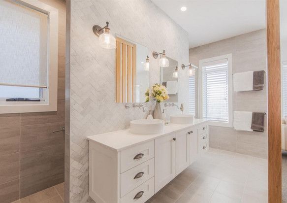 A bathroom with two sinks, a mirror and a walk in shower.