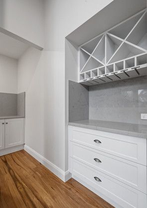 A kitchen with white cabinets and a wine rack on the wall.