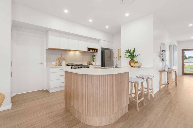 A kitchen with white cabinets and a wooden island.