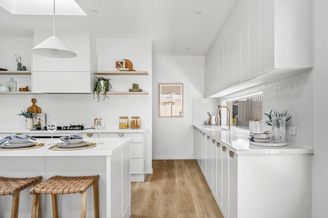 A kitchen with white cabinets and wooden floors.