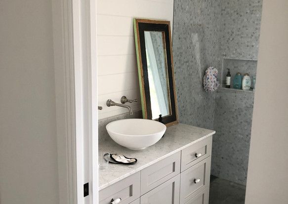 A bathroom with a sink, mirror and shower.